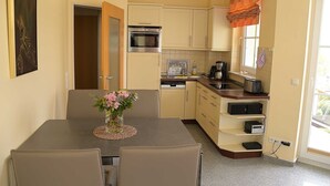 Una cocina compacta con comedor, que incluye estufa, horno y una pequeña cafetera.