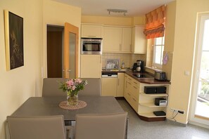 Una cucina compatta con zona pranzo, completa di fornello, forno e una piccola macchina per il caffè.