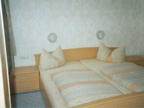 A double bed with striped bedding, a wooden headboard, and two bedside tables with drawers.