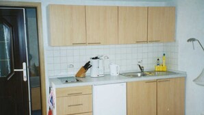 Une cuisine de taille réduite, dotée de meubles en bois, d’un lave-vaisselle blanc et d’appareils électroménagers de base.