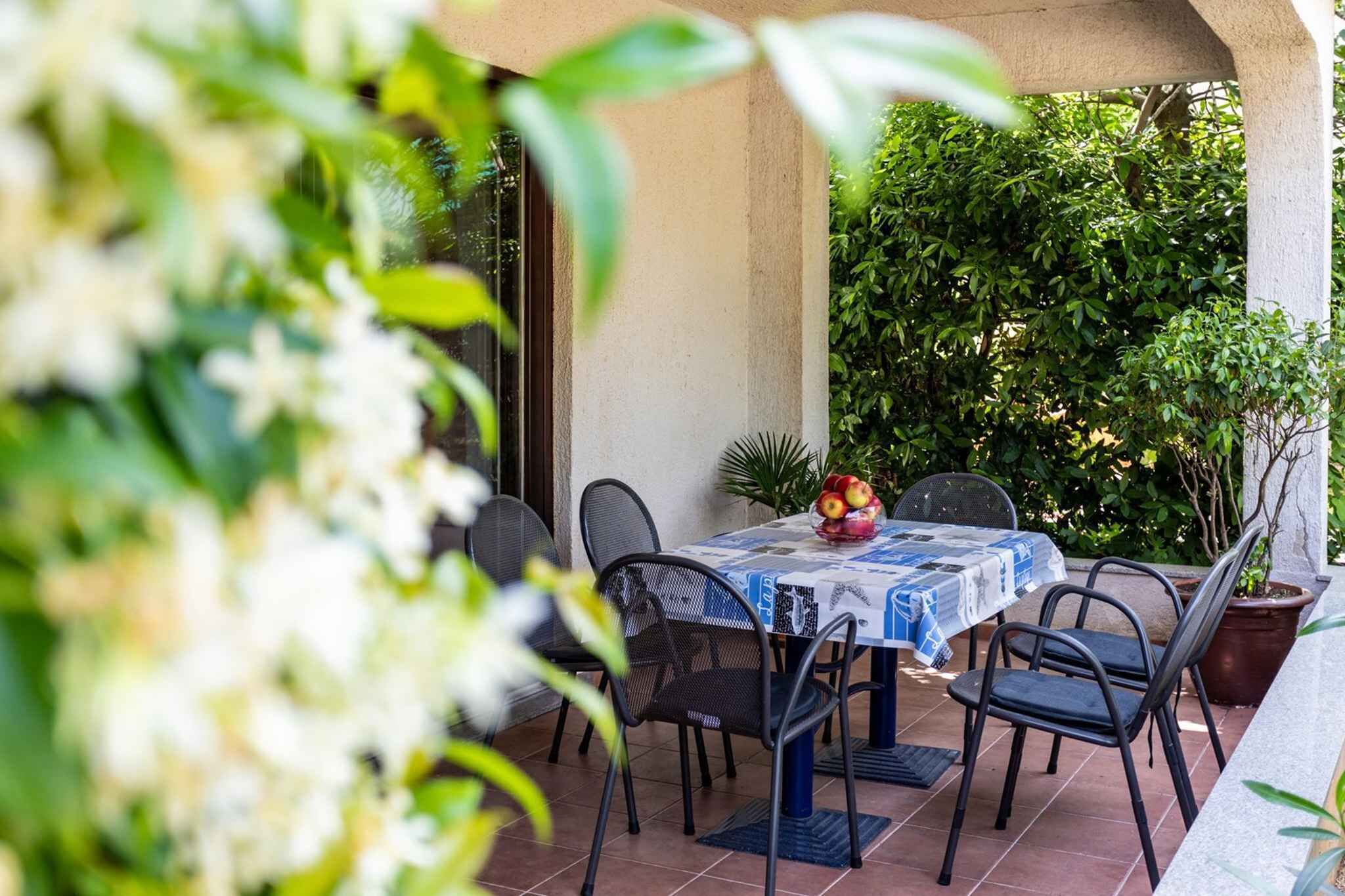 Eine Terrasse im Freien mit Tisch und Stühlen, umgeben von Pflanzen.