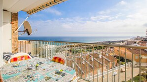 A balcony with a table set for dining, a satellite dish, and a view of the sea and buildings. - Nice apartment in Arenales del Sol with swimming pool (Arenales del Sol)
