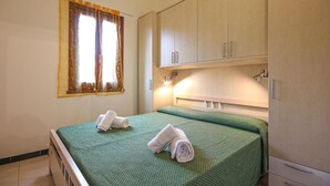 Habitación de hotel con cama, ventana con cortinas y armario.