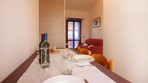 Un comedor con una mesa dispuesta para dos personas, con botellas de vino, copas y pan.