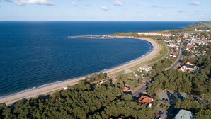 Vue aérienne d’une ville côtière avec une plage, des maisons et une route.
