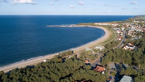 Luchtbeeld van een kustplaatsje met een strand, huizen en een weg.