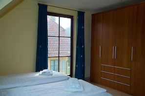 A room with two beds, a wardrobe, and a window with curtains.