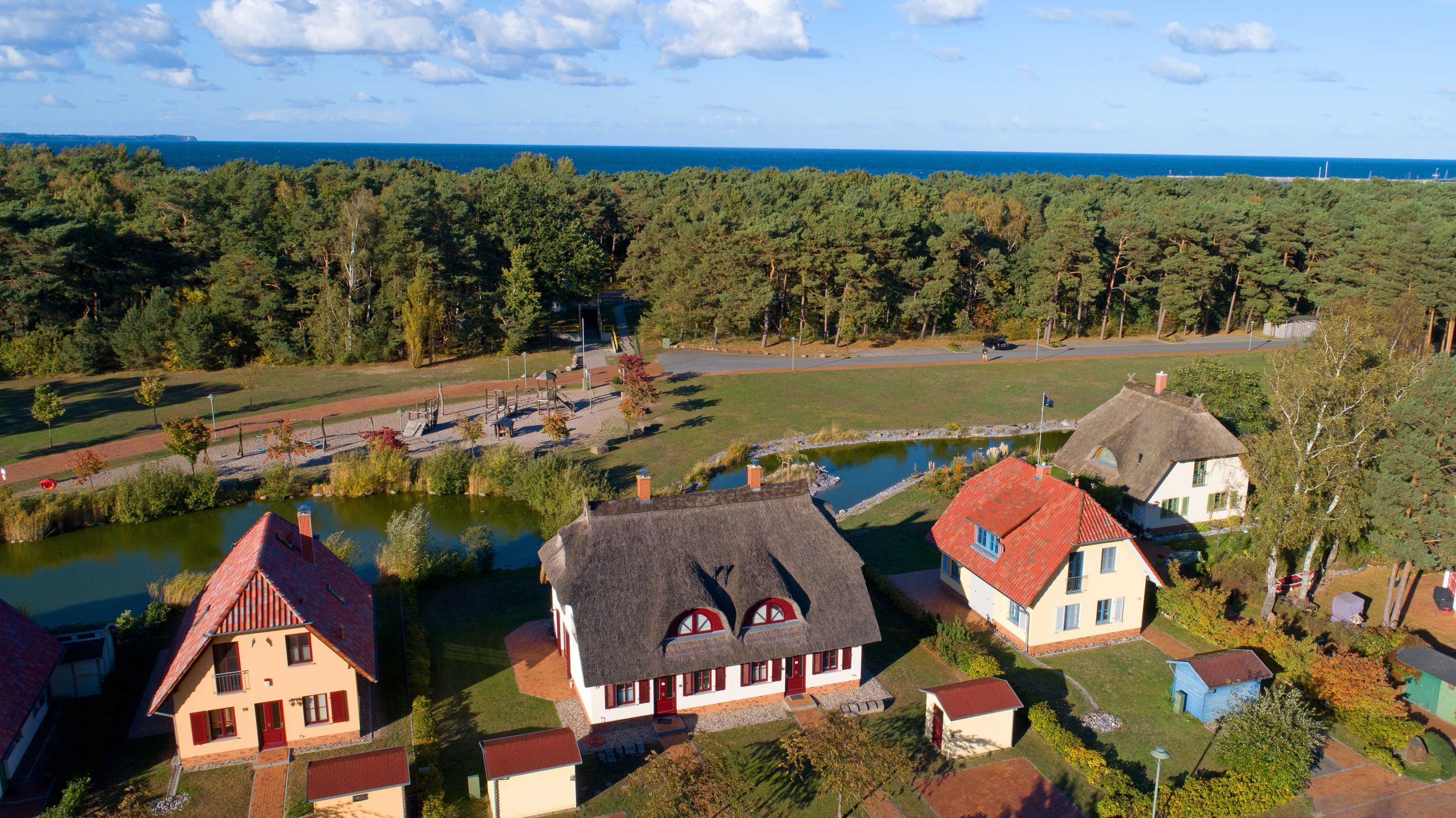 Un village rural avec des maisons traditionnelles, un étang et une vue sur la mer.