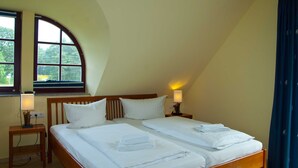 Une chambre avec deux lits, une fenêtre donnant sur un beau paysage, une lampe et une chaise.