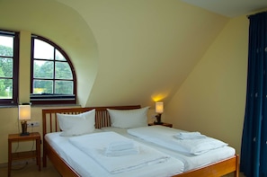 Een kamer met twee bedden, een raam met uitzicht, een lamp en een stoel.