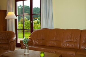 A brown leather sofa, a wooden table, and a vase with flowers.