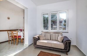 A living room with a sofa, a dining table with chairs, and a window with a view of buildings. - Nice apartment in Silo with WiFi (Silo)