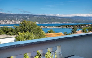 A balcony with a view of a coastal town, a clear blue sea, and distant mountains. - Nice apartment in Silo with WiFi (Silo)