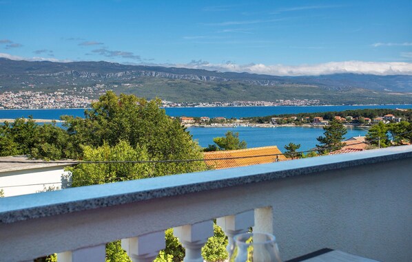 A balcony with a view of a coastal town, a clear blue sea, and distant mountains. - Nice apartment in Silo with WiFi (Silo)