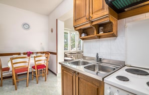 A kitchen with wooden cabinets, a double sink, and a stove. - Nice apartment in Silo with WiFi (Silo)