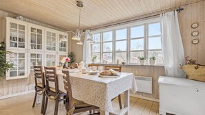 A cozy dining area with wooden cabinets, a table set for four, and a view of the outside through large windows. - Cozy home in Ebeltoft with kitchen (Ebeltoft)