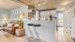 A modern kitchen with white cabinets, a wooden ceiling, and a bar area with stools. - Cozy home in Ebeltoft with kitchen (Ebeltoft)