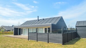 A modern house with a sloped roof, large windows, and a fenced yard. - Beautiful home in Brovst with sauna (Brovst)