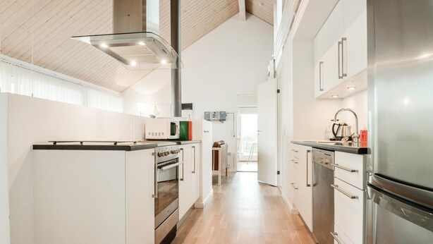 A modern kitchen with white cabinetry, stainless steel appliances, and a wooden floor. - Beautiful home in Brovst with sauna (Brovst)