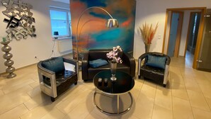 Una sala de estar moderna con una pared curva, una mesa de centro redonda, dos sofás y una lámpara de pie decorativa.