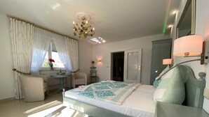 Habitación de hotel con cama, escritorio, silla, tocador con espejo y candelabro.