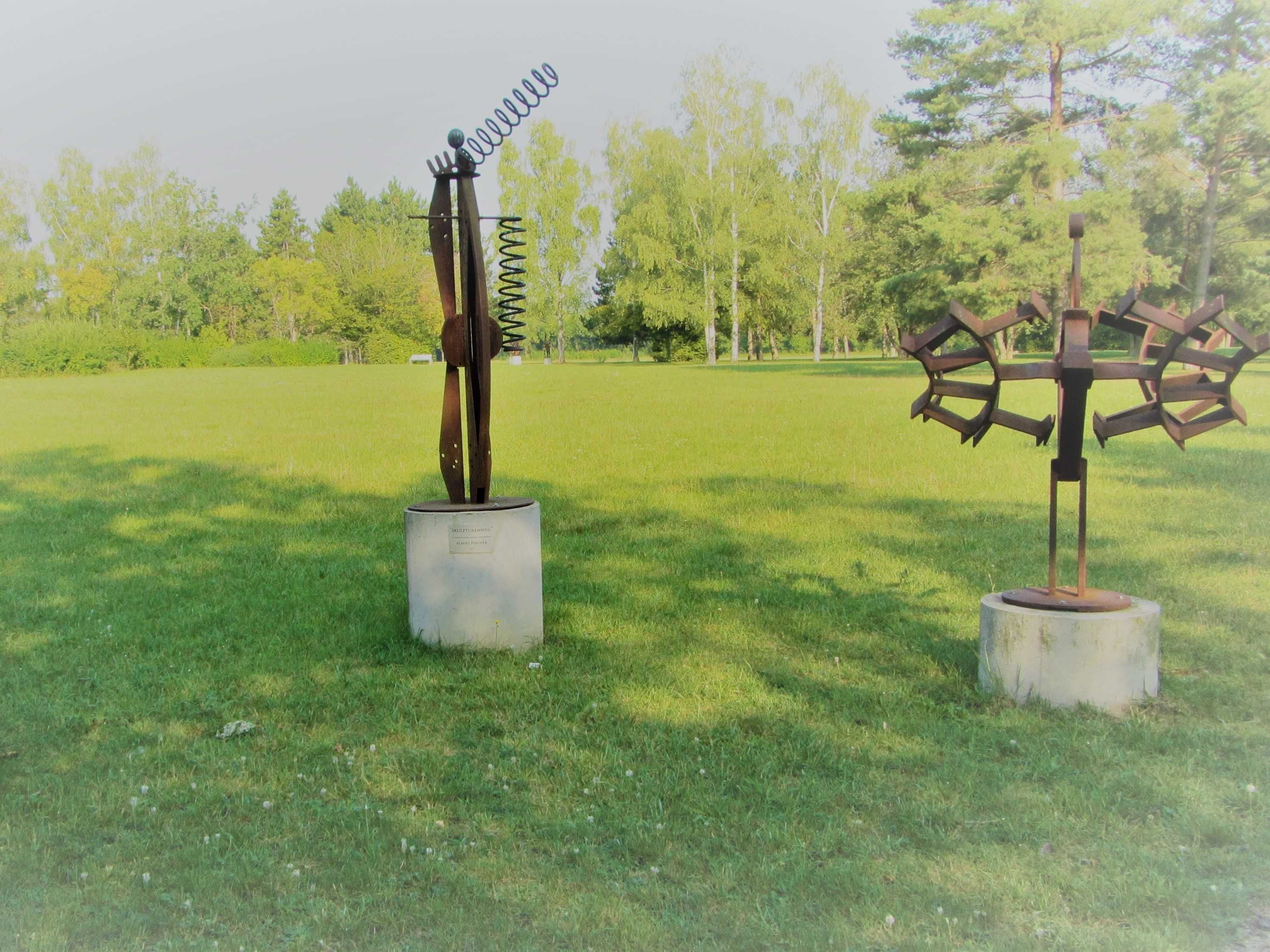 Two metal sculptures in a grassy field.