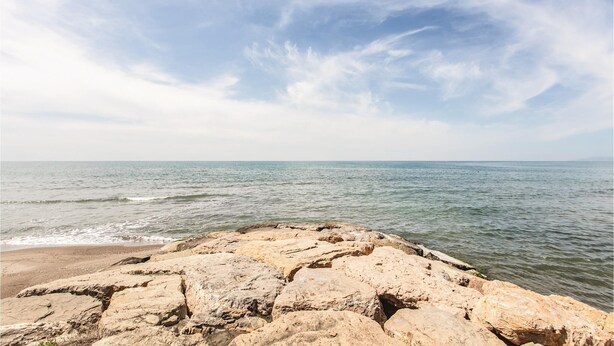 Eine felsige Küstenlinie mit ruhiger See und blauem Himmel.