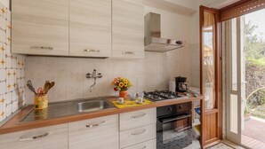 Eine moderne Küche mit Gasherd, Backofen und Spüle. Ein Fenster bietet Blick ins Freie.