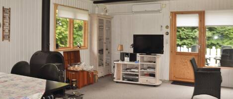 A room with a television, a table, a chair, and a cabinet.
