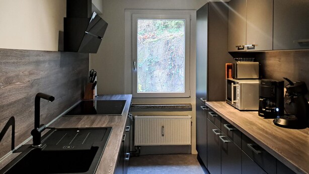 Eine moderne Küche mit Fenster, Einbaugeräten und Holzarbeitsplatten.