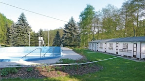 Ein Schwimmbecken mit Sprungbrett, ein kleines Gebäude mit der Aufschrift 'BOWEN' und bewaldete Hügel im Hintergrund.