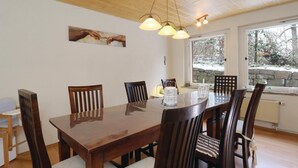Ein Essbereich mit einem Holztisch, vier Stühlen, einer Chandelieber und einem Gemälde an der Wand.