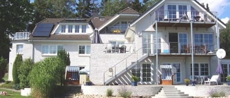 Ein zweistöckiges Haus mit Balkon, Treppe und Rasen.