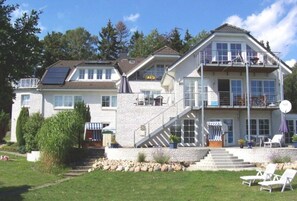 A two-story house with a balcony, a staircase, and a lawn.