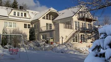 A two-story building with a balcony, a staircase, and a snow-covered ground.