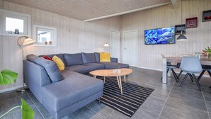 A modern living room with a grey sectional sofa, a round coffee table, and a dining area with a table and chairs. - Gorgeous home in Ejstrupholm with sauna (Ejstrupholm)