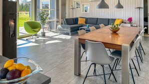 A modern living room with a wooden dining table, grey sofa, and a bright green chair. - Gorgeous home in Ejstrupholm with sauna (Ejstrupholm)