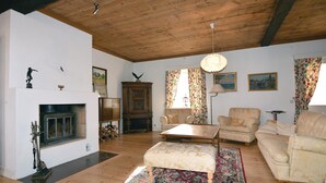 Un salon spacieux doté d’une cheminée, de planchers en bois et d’un plafond haut. On y trouve deux canapés, une table basse et un tapis à motifs.