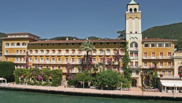 Ein großes Hotel mit einem markanten Turm und zahlreichen Balkonen, direkt am Wasser gelegen.