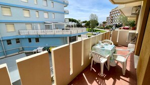 Ein Balkon mit Tisch und Stühlen, mit Blick auf ein blaues Gebäude mit zahlreichen Fenstern und Balkonen.