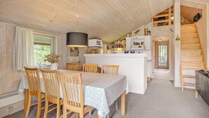 Una cocina acogedora con armarios de madera, una isla central y una zona de comedor con mesa y sillas.