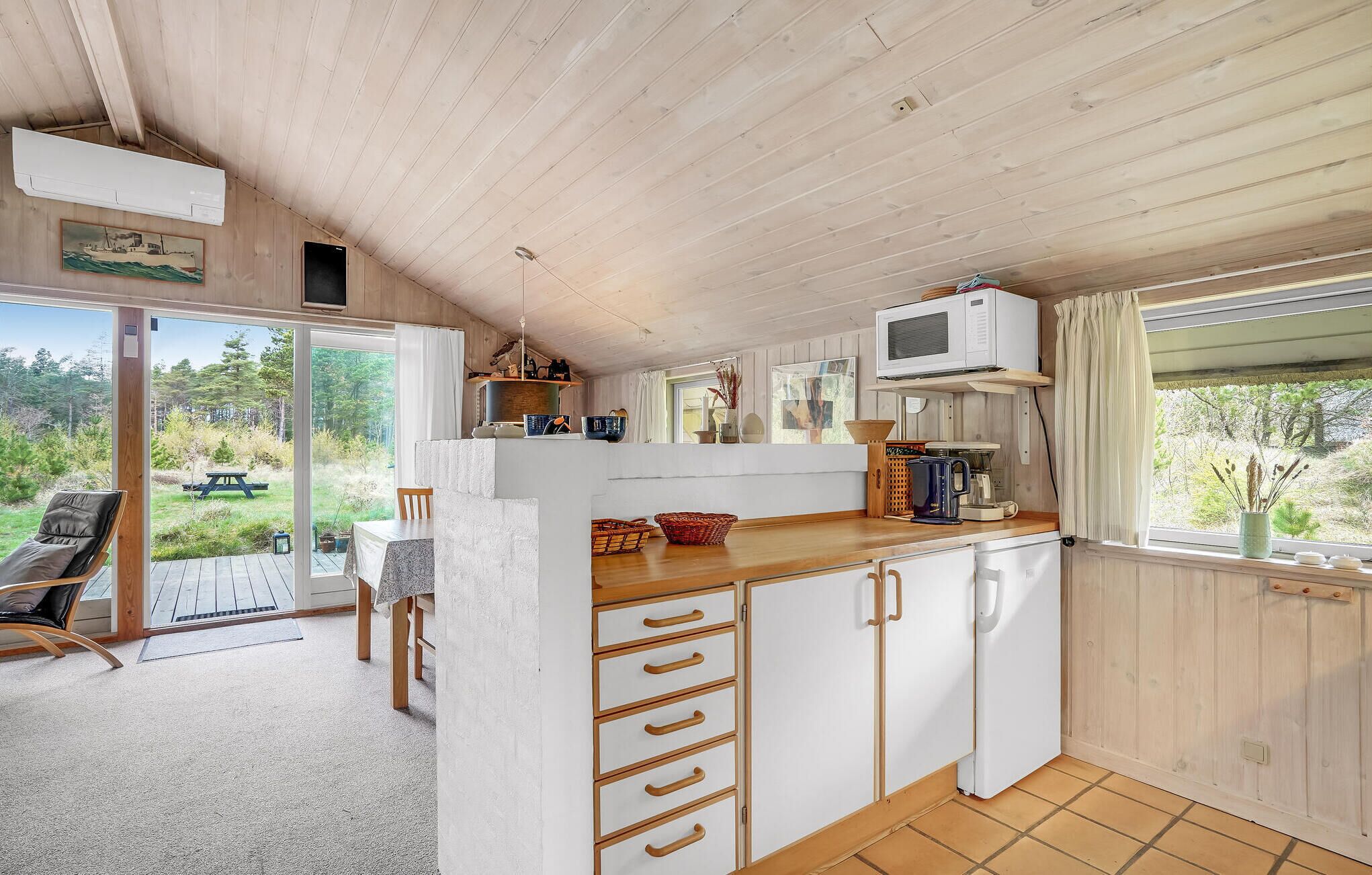 A compact kitchen with a dining area, a large window, and a view of the outdoors.