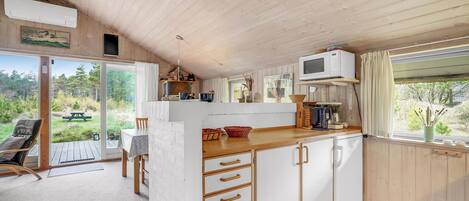 A compact kitchen with a dining area, a large window, and a view of the outdoors.