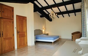 Un dormitorio con cama, armario de madera y candelabro.