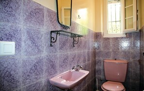 Un baño con azulejos morados, un lavamanos rosa y un inodoro rosa.