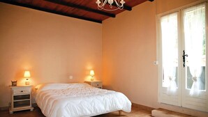 Een slaapkamer met een bed, twee nachtkastjes met lampen, een raam met gordijnen en een houten plafond.