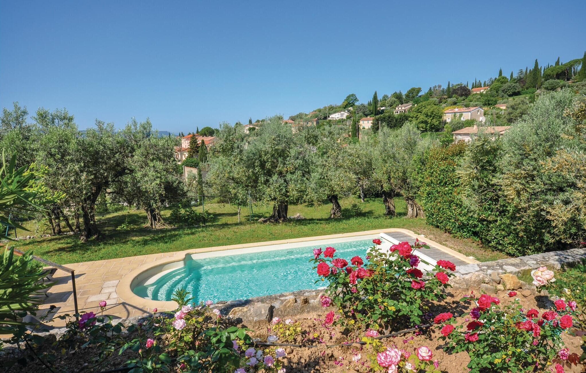 A swimming pool surrounded by lush greenery and flowering plants.