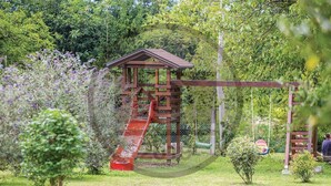 Een houten speelconstructie met een glijbaan en schommel in een park.