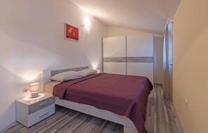 A bedroom with a bed, bedside table, lamp, and wardrobe.