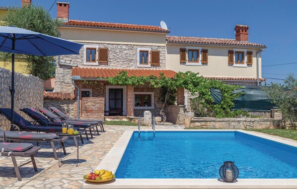 A poolside area with lounge chairs, a table with fruit, and a clear blue pool.